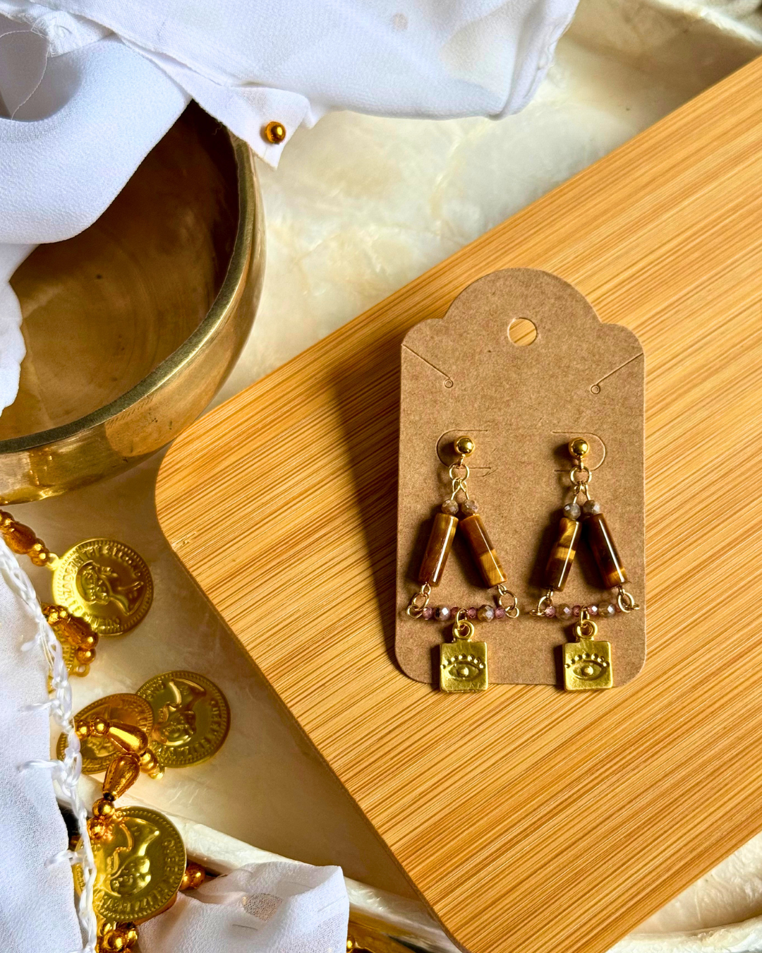 Gold and brown beaded earrings on a wooden display card with a marble background.