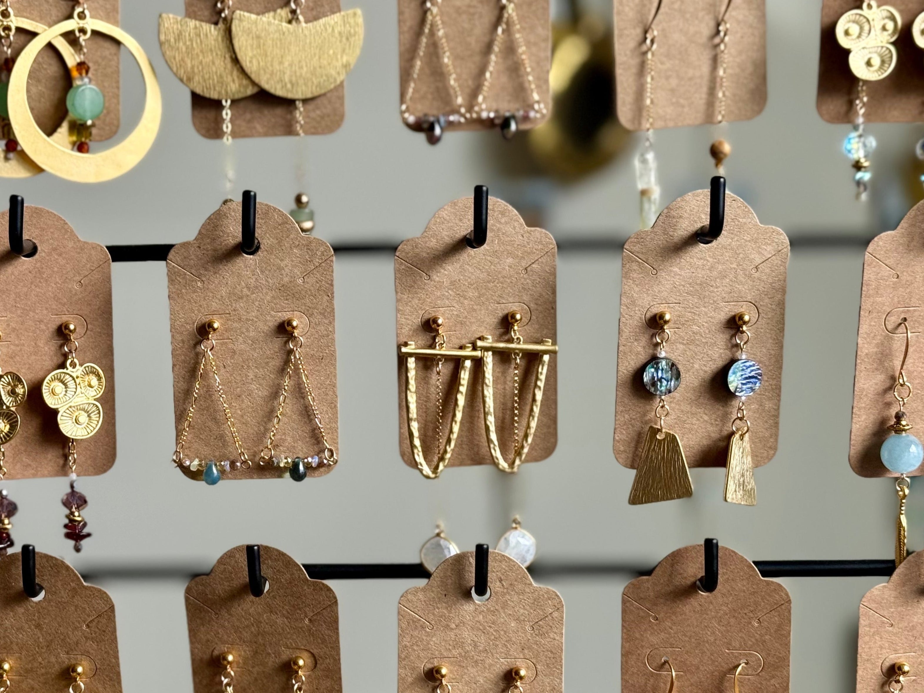 Collection of various earrings on display with brown cardstock tags.