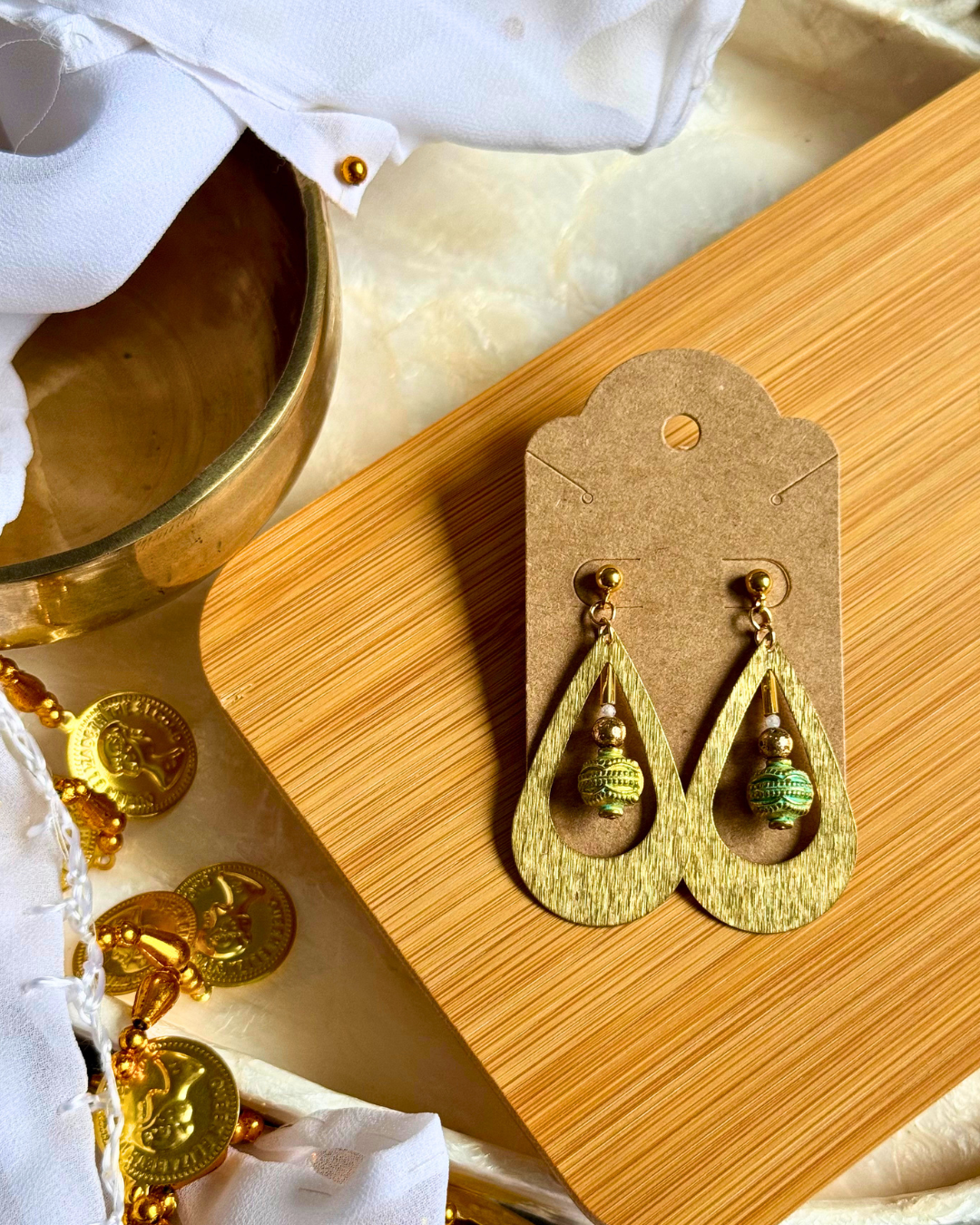 Gold earrings on a wooden stand with a marble background