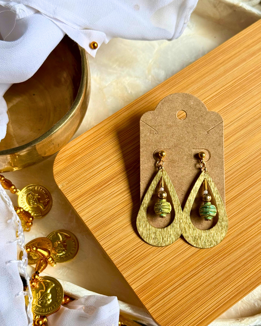 Gold earrings on a wooden stand with a marble background